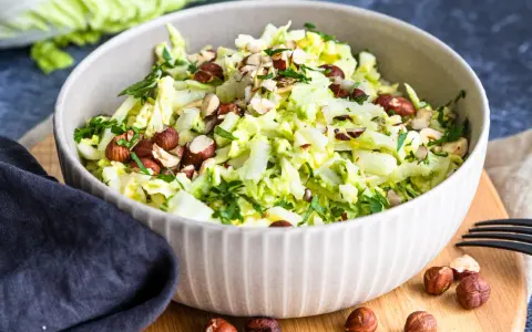 Frischer Chinakohlsalat mit gehackten Haselnüssen und Petersilie, garniert mit ganzen Nüssen.