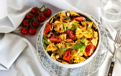 Mediterraner Salat mit getrockneten Tomaten und Rucola, garniert mit Mandeln und frischen Kirschtomaten. Ein leichter Genuss.