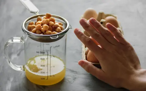 Kichererbsenwasser in einem Messbecher und Eier im Karton. Perfekt für veganes ei ersatz backen.