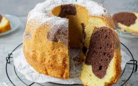 Ein saftiger Marmorkuchen mit Puderzucker bestäubt, ein Stück abgetrennt, das die schöne Marmorierung zeigt.