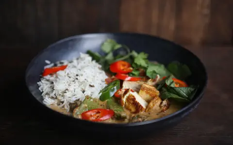 Ein köstliches Thai Curry Rezept mit Reis, gebratenem Tofu, Chili und frischen Kräutern in einer cremigen Sauce.