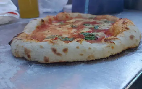 Frisch gebackene Pizza mit weltbestem Pizzateig mit Trockenhefe, belegt mit Tomaten, Mozzarella und Basilikum.