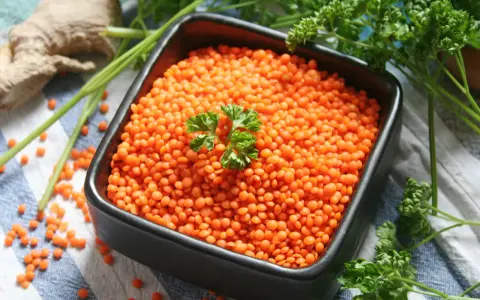 Schüssel mit roten Linsen, bereit zum Kochen. Ingwer und Petersilie liegen daneben.