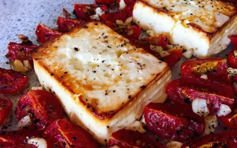 Ofen-gebackener Feta mit Kirschtomaten, Knoblauch und Kräutern. Ein köstliches griechisches Gericht, das im Ofen zubereitet wird.