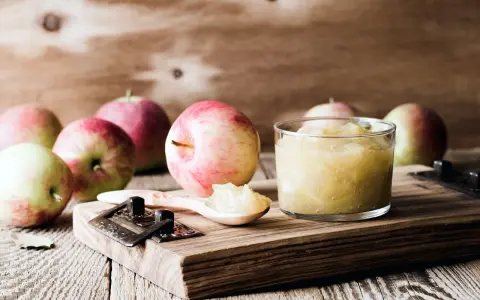 Frische Äpfel und selbstgemachtes Apfelmus im Glas, bereit zum Apfelmus im Backofen einkochen.