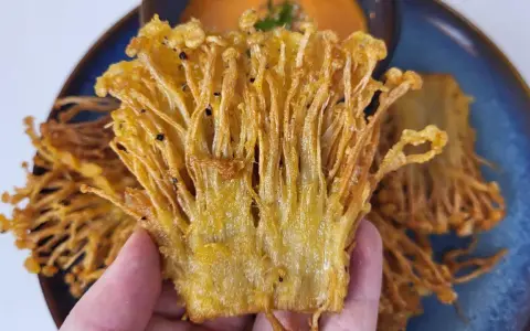 Knusprige Enoki Pilze, perfekt für ein einfaches enoki pilze rezept. Goldbraun frittiert und auf einem blauen Teller serviert.