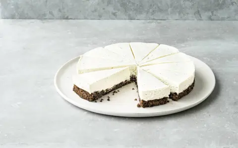 Cremiger Kuchen ohne Mehl, in Tortenstücke geschnitten, mit dunklem Boden und heller Füllung, garniert mit Vanillepunkten.