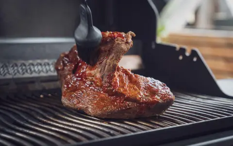 Ein saftiges Brisket, sous vide gegart, wird mit einer BBQ-Sauce auf dem Grill glasiert.