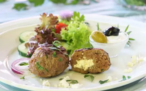 Gefüllte Bifteki mit Feta, serviert mit Salat, Gurken, Zwiebeln und Tzatziki. Ein köstliches Bifteki Rezept für Genießer.