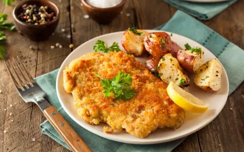 Goldbraunes Schnitzel, perfekt paniert, mit Rosmarinkartoffeln und Zitrone. Die richtige schnitzel panieren reihenfolge macht's!
