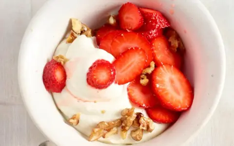 Cremiger Skyr mit frischen Erdbeeren und knackigen Walnüssen in einer weißen Schale, ein Genuss für Augen und Gaumen.
