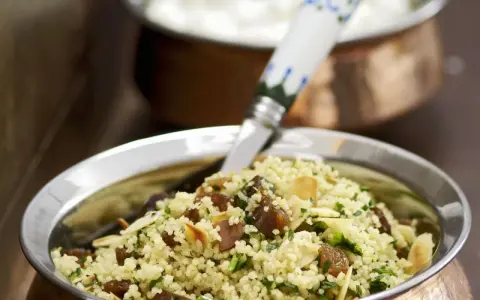 Ein köstlicher Couscous mit Rosinen, Mandelsplittern und frischer Petersilie, serviert in einer Kupferschale.