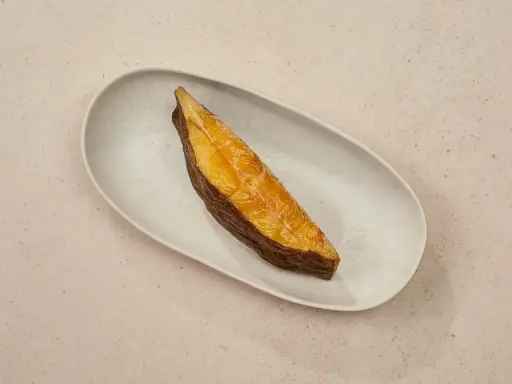 Ein goldbraunes Stück schwarzer Heilbutt liegt auf einer ovalen Schale. Dieser Fisch ist nicht nur lecker, sondern auch gesund.