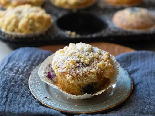 Saftige Blaubeermuffins mit Joghurt und Streuseln, bestäubt mit Puderzucker.