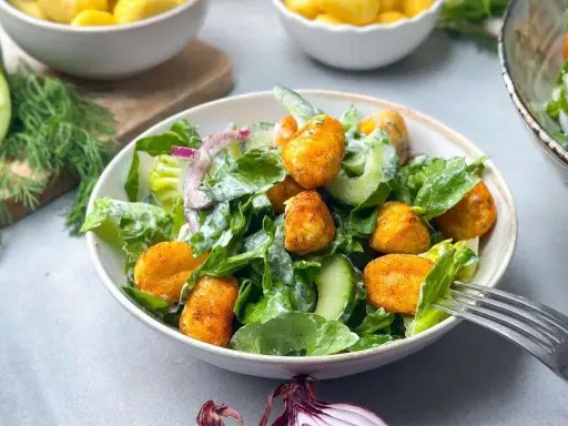 Knuspriger Gnocchi Salat mit Gurke, Salat und Zwiebeln, serviert in einer Schüssel mit einer Gabel.