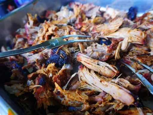 Saftiges, zartes Pulled Pork im Texas-Stil, bereit zum Servieren. Ein Gabel hebt die köstlichen Fleischfasern an.