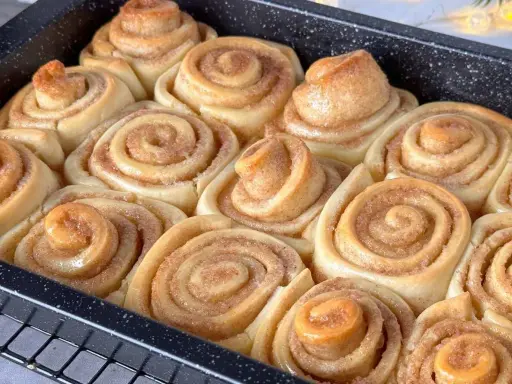 Frisch gebackene Zimtschnecken im Blech, bereit für das Zimtschnecken Rezept. Sie duften nach Zimt und Zucker.