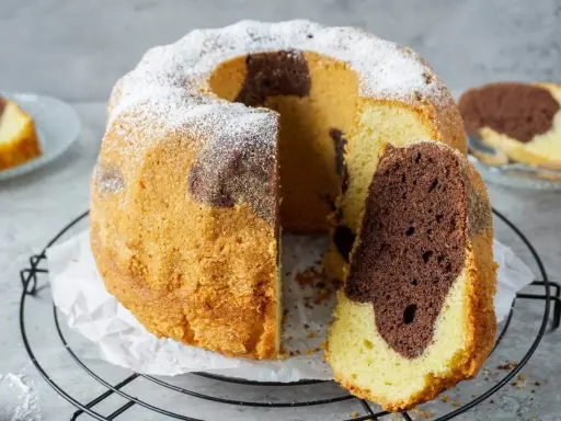 Ein saftiger Marmorkuchen mit Puderzucker bestäubt, ein Stück abgetrennt, das die schöne Marmorierung zeigt.