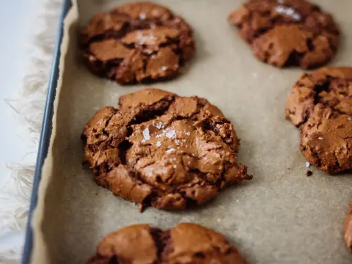 Frisch gebackene, schoko cookies rezept einfach, mit Meersalz bestreut, auf Backpapier.