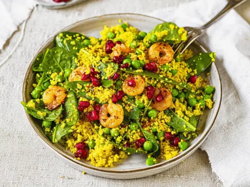 Bunter Couscous-Salat mit Garnelen, Erbsen, Spinat und Granatapfelkernen. Ein leichter und gesunder Genuss.