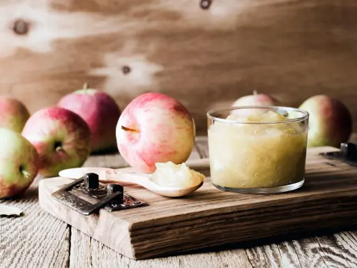 Frische Äpfel und selbstgemachtes Apfelmus im Glas, bereit zum Apfelmus im Backofen einkochen.