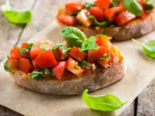 Zwei Bruschetta mit Tomaten und Basilikum, ein authentisches italienisches Rezept, auf rustikalem Holz.