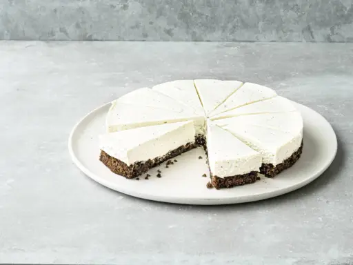 Cremiger Kuchen ohne Mehl, in Tortenstücke geschnitten, mit dunklem Boden und heller Füllung, garniert mit Vanillepunkten.