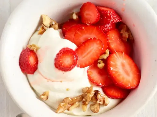 Cremiger Skyr mit frischen Erdbeeren und knackigen Walnüssen in einer weißen Schale, ein Genuss für Augen und Gaumen.