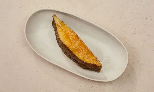 Ein goldbraunes Stück schwarzer Heilbutt liegt auf einer ovalen Schale. Dieser Fisch ist nicht nur lecker, sondern auch gesund.