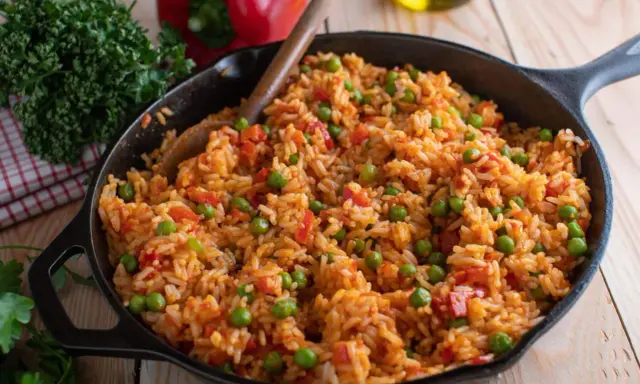 Djuvec Reis mit Erbsen und Paprika in einer Gusseisenpfanne, bereit zum Servieren.