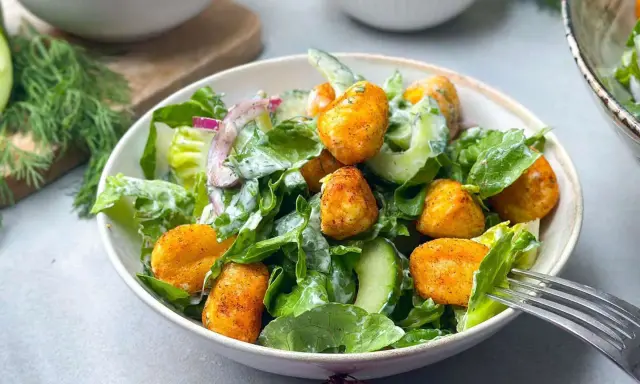 Knuspriger Gnocchi Salat mit Gurke, Salat und Zwiebeln, serviert in einer Schüssel mit einer Gabel.