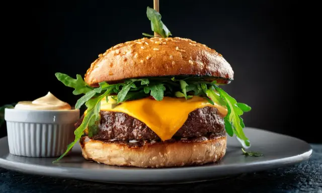 Saftiger Wagyu Burger mit geschmolzenem Käse, Rucola und einer Beilage Sauce. Ein perfektes Wagyu Burger Rezept für Genießer.