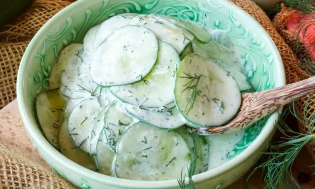 Frischer gurkensalat mit saurer sahne und dill, serviert in einer grünen schüssel.