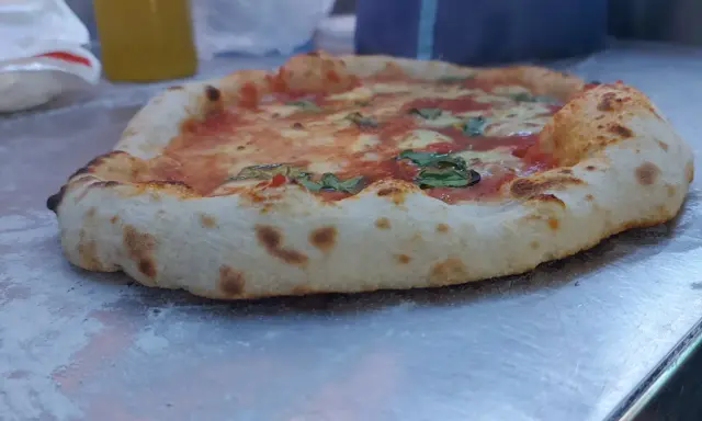 Frisch gebackene Pizza mit weltbestem Pizzateig mit Trockenhefe, belegt mit Tomaten, Mozzarella und Basilikum.