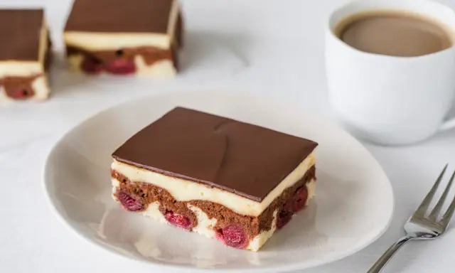 Ein Stück Donauwelle-Kuchen mit Kirschen, Schokolade und Vanillecreme. Perfekt für ein Donauwelle Rezept.