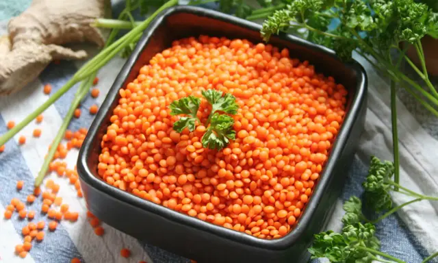 Schüssel mit roten Linsen, bereit zum Kochen. Ingwer und Petersilie liegen daneben.