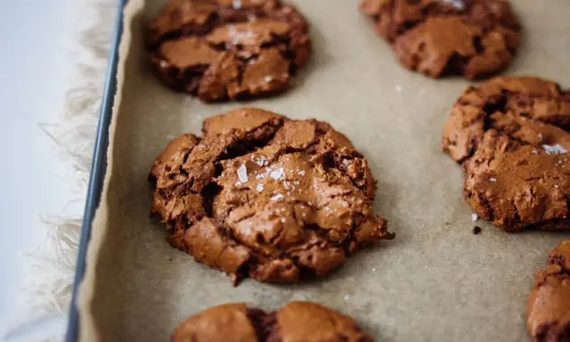 Frisch gebackene, schoko cookies rezept einfach, mit Meersalz bestreut, auf Backpapier.