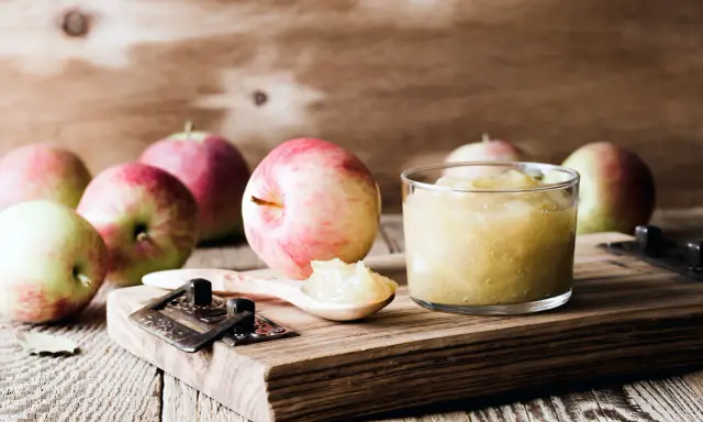 Frische Äpfel und selbstgemachtes Apfelmus im Glas, bereit zum Apfelmus im Backofen einkochen.
