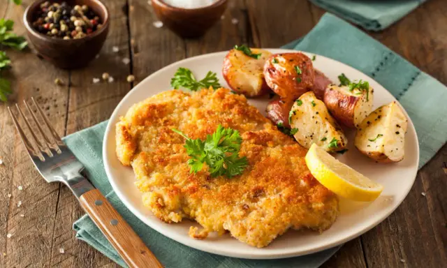 Goldbraunes Schnitzel, perfekt paniert, mit Rosmarinkartoffeln und Zitrone. Die richtige schnitzel panieren reihenfolge macht's!