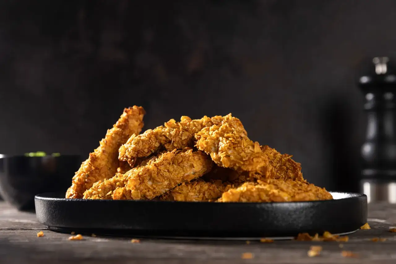 Knusprige chicken nuggets auf einem schwarzen Teller, bereit zum Genie&szlig;en.