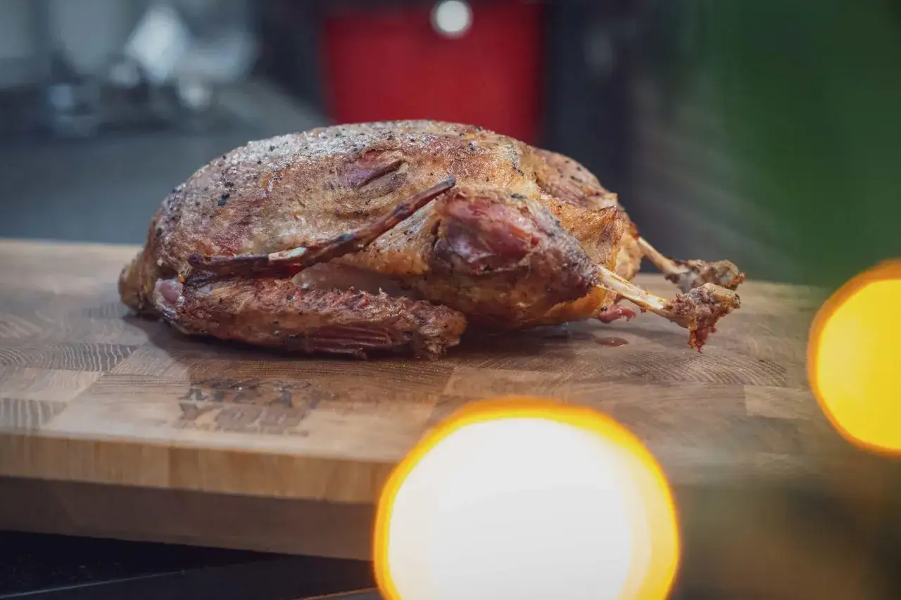 Eine perfekt gegarte Ente, die nach der Sous-vide-Methode zubereitet wurde, liegt auf einem Holzbrett.
