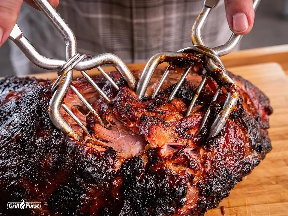 Pulled Pork aus dem Smoker: Zarte Fleischfasern werden mit Fleischgabeln auseinandergezogen.