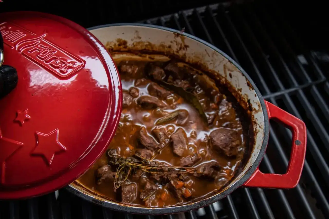 Herzhaftes Wild im Dutch Oven auf dem Grill, mit Kräutern und Lorbeer verfeinert. Ein Festmahl für Genießer.