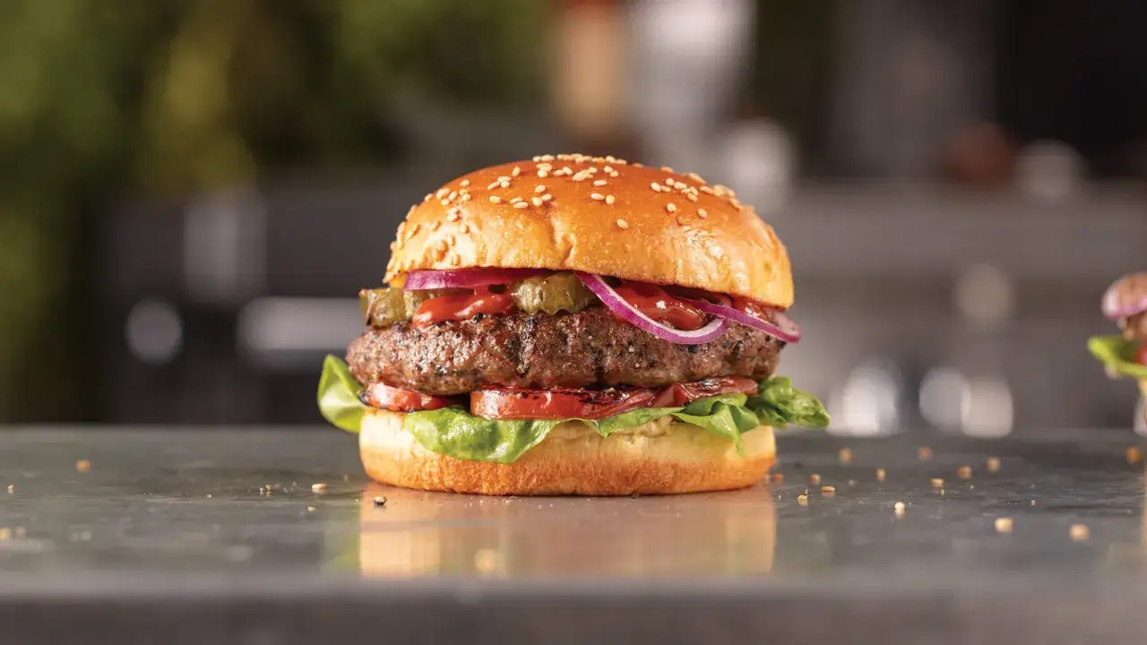 Saftiger Wagyu Burger mit Sesambrötchen, Tomaten, Salat, Gurken und Zwiebeln. Ein perfektes Wagyu Burger Rezept für Genießer.