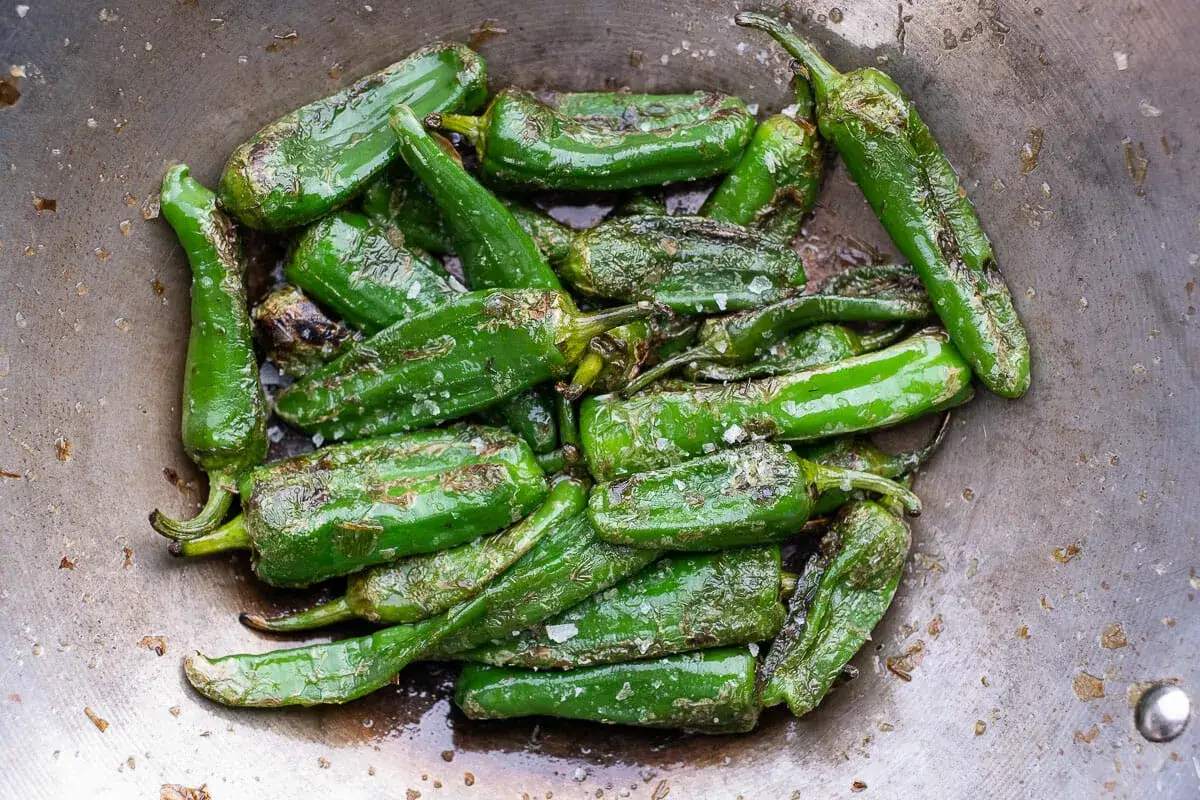 Gebratene Pimientos de Padr&oacute;n mit grobem Salz in einer Pfanne. Ein einfaches und leckeres Rezept f&uuml;r spanische Tapas.