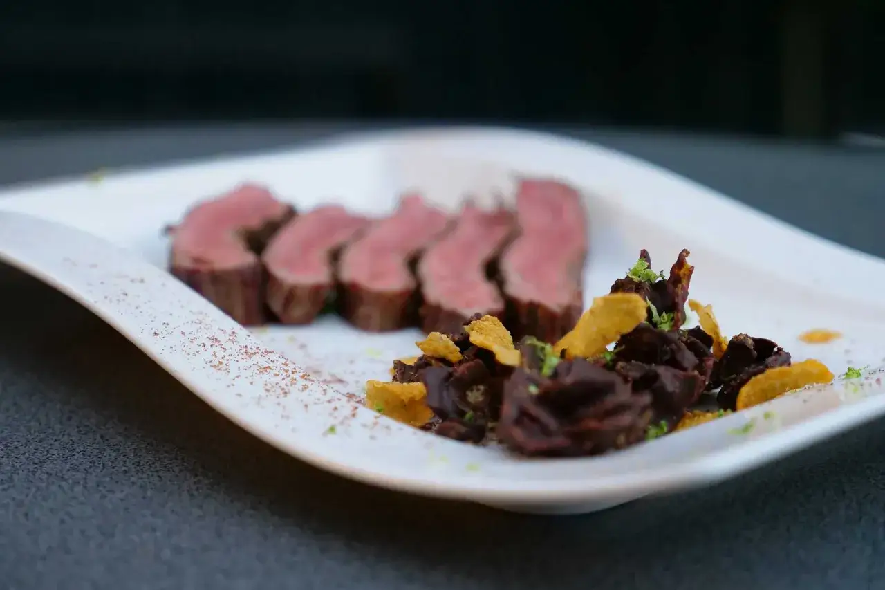 Perfekt zubereitetes Flank Steak, in Scheiben geschnitten, mit einer ungew&ouml;hnlichen Beilage aus dunkler Schokolade und knusprigen Chips.