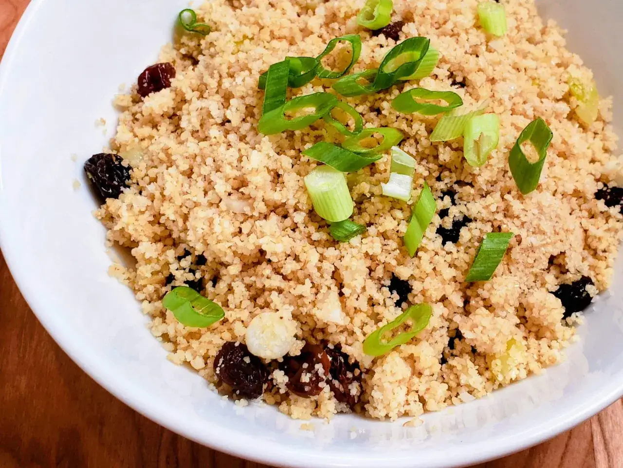 Ein Teller mit k&ouml;stlichem Couscous mit Rosinen und Fr&uuml;hlingszwiebeln, bereit zum Genie&szlig;en.