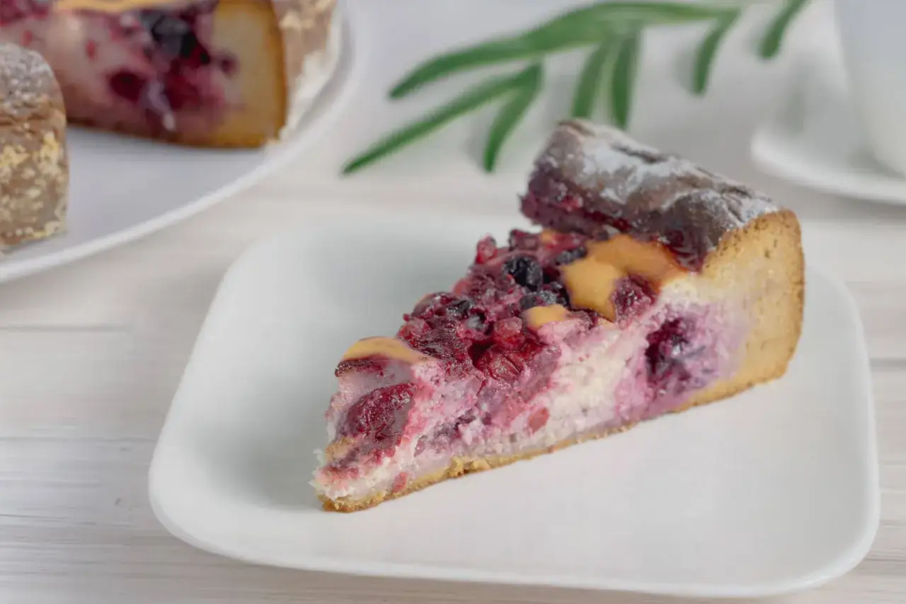 Ein saftiges Stück Kuchen mit Beeren, bestäubt mit Puderzucker. Ein köstlicher Kuchen ohne Zucker, der die natürliche Süße der Früchte hervorhebt.