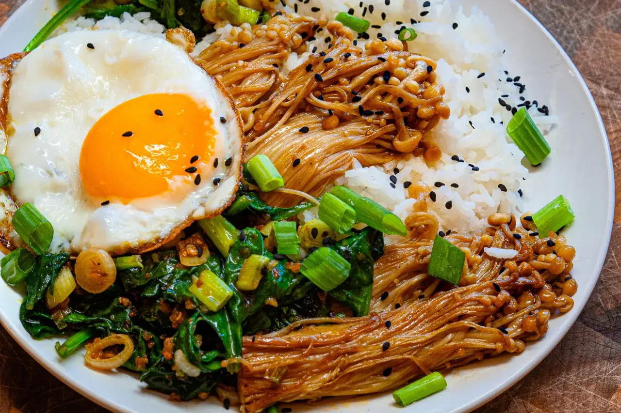 Rezept f&uuml;r Enoki Pilze: Reis mit gebratenen Enoki Pilzen, Spinat und Spiegelei, garniert mit Fr&uuml;hlingszwiebeln und schwarzem Sesam.