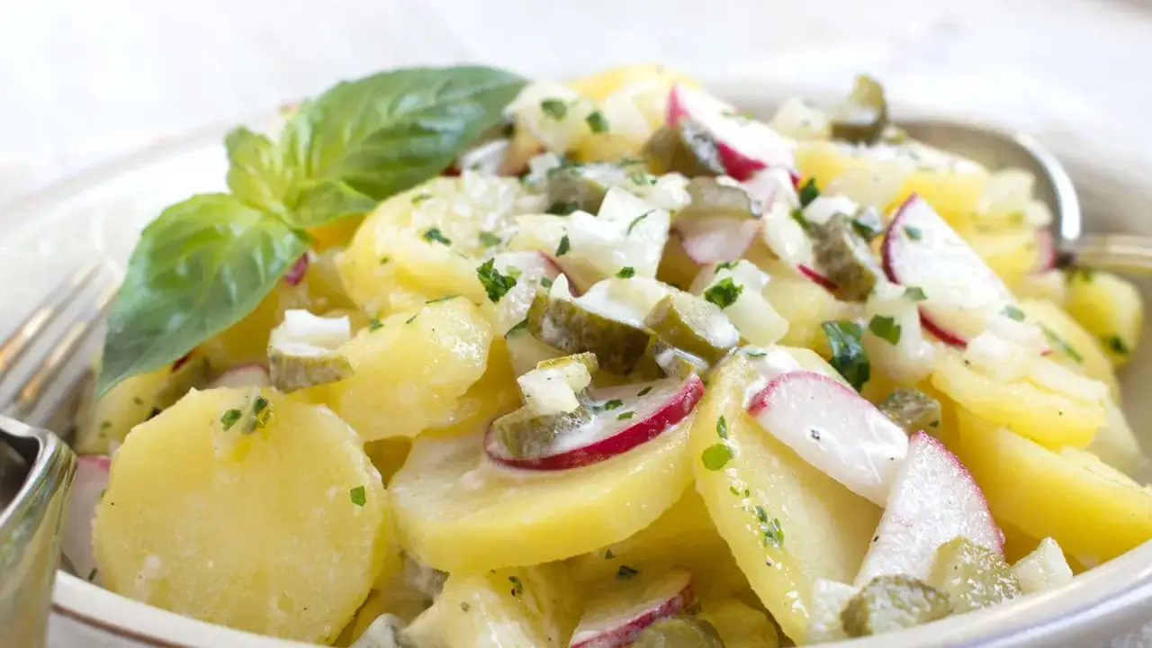 Ein cremiger Kartoffel Radieschen Salat mit Gurken und frischen Kr&auml;utern, garniert mit Basilikum.